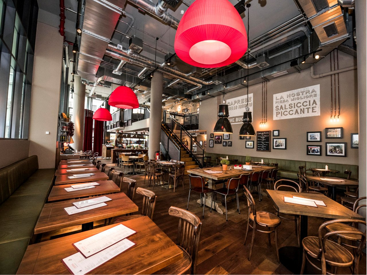 Gastraum der L'Osteria mit Holztischen und warmem Licht
