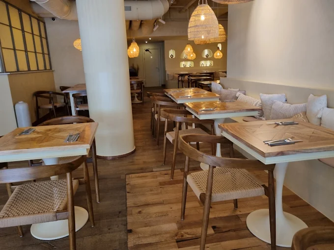 Innenansicht des Woodrich Café mit Holztischen und Rattanlampen